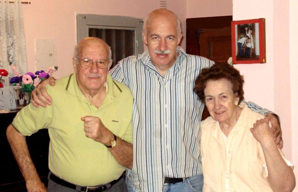Daniel abrazando a su papá y a su mamá en el living de una casa